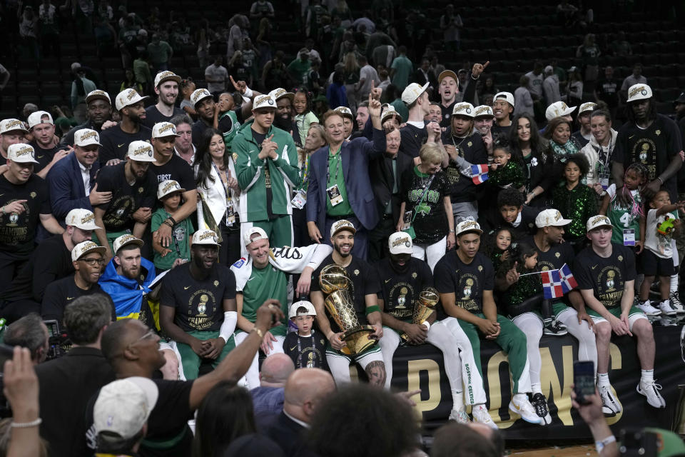 Boston Celtics forward Jayson Tatum, center, holds the Larry O'Brien Championship Trophy as he celebrates with the team after they won the NBA basketball championship with a Game 5 victory over the Dallas Mavericks, Monday, June 17, 2024, in Boston. (AP Photo/Charles Krupa)