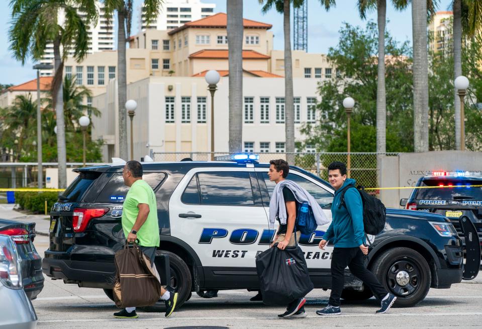 Two students walk by police cars outside of Dreyfoos School of the Arts where a West Palm Beach Sgt. Christopher Nagel shot and killed Romen Phelps  who crashed a van on the property and ran into the theater.