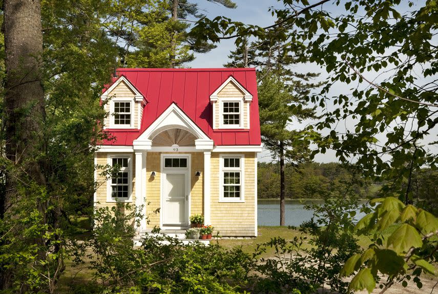 <p>This darling red-roofed cottage sits in a grove of leafy trees near the water's edge in <a href="https://www.tripadvisor.com/Tourism-g40643-Freeport_Maine-Vacations.html" rel="nofollow noopener" target="_blank" data-ylk="slk:Freeport, Maine;elm:context_link;itc:0;sec:content-canvas" class="link ">Freeport, Maine</a>. Designed by Mac Lloyd of Creative Cottages, the environmentally sensitive abode packs in a full kitchen, bathroom, living space, sleeping quarters, gas fireplace, laundry, and a loft space, while still managing to seem airy and spacious. </p>