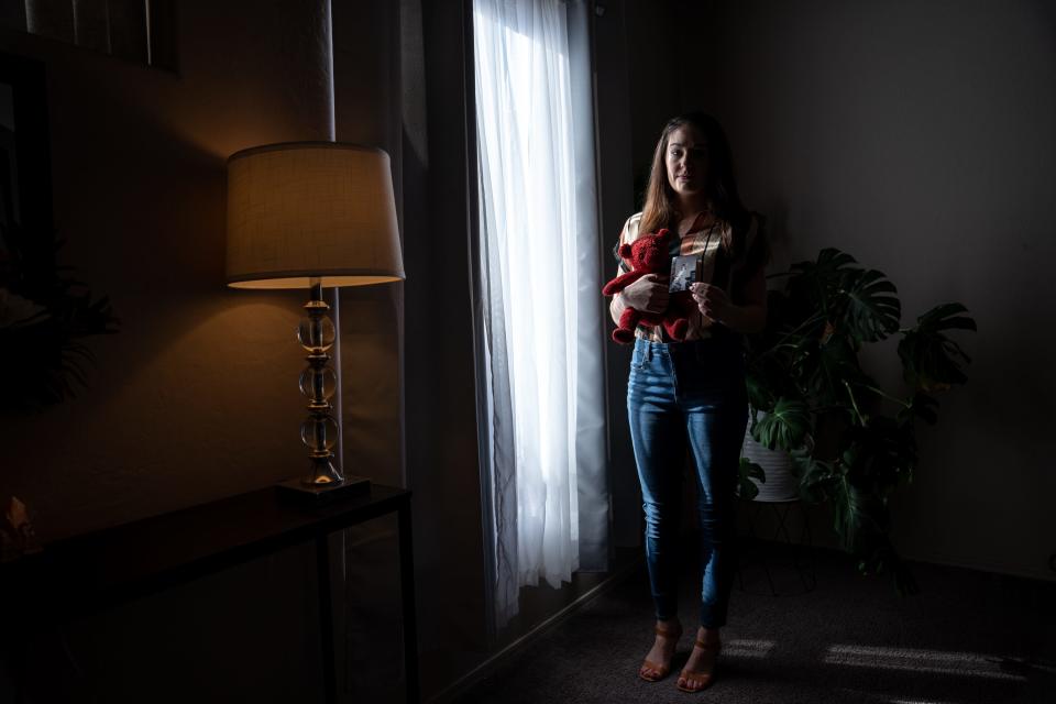 Kimber Biggs poses for a portrait as she holds a photograph of her sister Mikelle Biggs and Mikelle's teddy bear, at her home in Gilbert on Jan. 25, 2024. Mikelle Biggs, who was 11 years old, disappeared while riding her bike near her home in Mesa on Jan. 2, 1999.