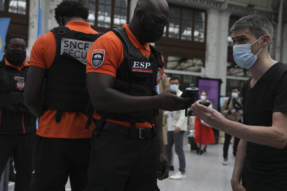 Security officers check passengers' health passes at the Gare de Lyon train station in Paris Monday Aug.9, 2021. Starting today, the pass will be required in France to access cafes, restaurants, long-distance travel and, in some cases, hospitals. It was already in place for cultural and recreational venues, including cinemas, concert halls, sports arenas and theme parks with a capacity for more than 50 people. (AP Photo/Adrienne Surprenant)