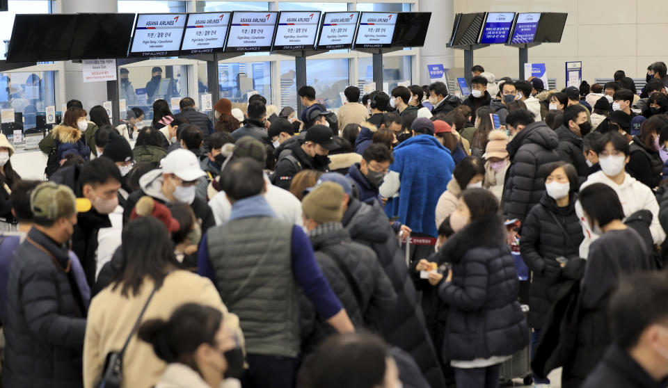 Passengers wait for their flight tickets at Jeju International Airport on Jeju Island, South Korea, Tuesday, Jan. 24, 2023. Thousands of travelers swarmed a small airport in South Korea's Jeju island on Wednesday in a scramble to get on flights following delays by snowstorms as frigid winter weather gripped East Asia for the second straight day. (Park Ji-ho/Yonhap via AP)