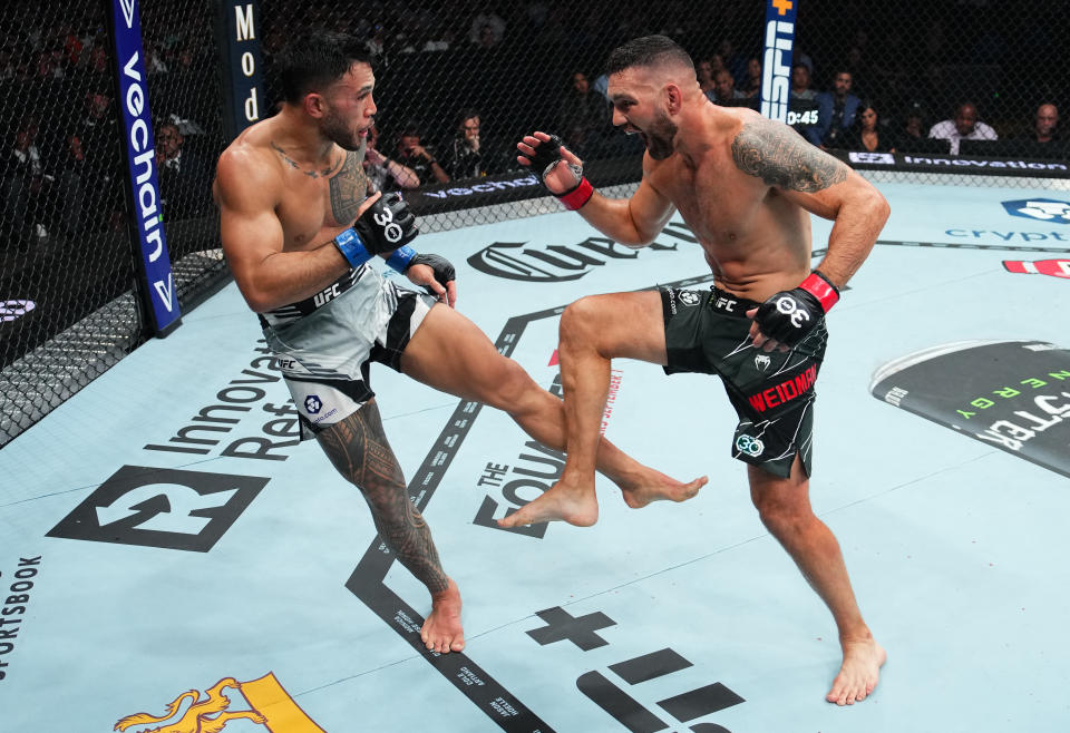 BOSTON, MASSACHUSETTS - AUGUST 19: (L-R) Brad Tavares kicks Chris Weidman in a middleweight fight during the UFC 292 event at TD Garden on August 19, 2023 in Boston, Massachusetts. (Photo by Cooper Neill/Zuffa LLC via Getty Images)