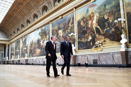 French President Emmanuel Macron (R) speaks to Russian President Vladimir Putin (L) in the Galerie des Batailles (Gallery of Battles) as they arrive for a joint press conference at the Chateau de Versailles before the opening of an exhibition marking 300 years of diplomatic ties between the two countries in Versailles, France, May 29, 2017. REUTERS/Stephane De Sakutin/Pool