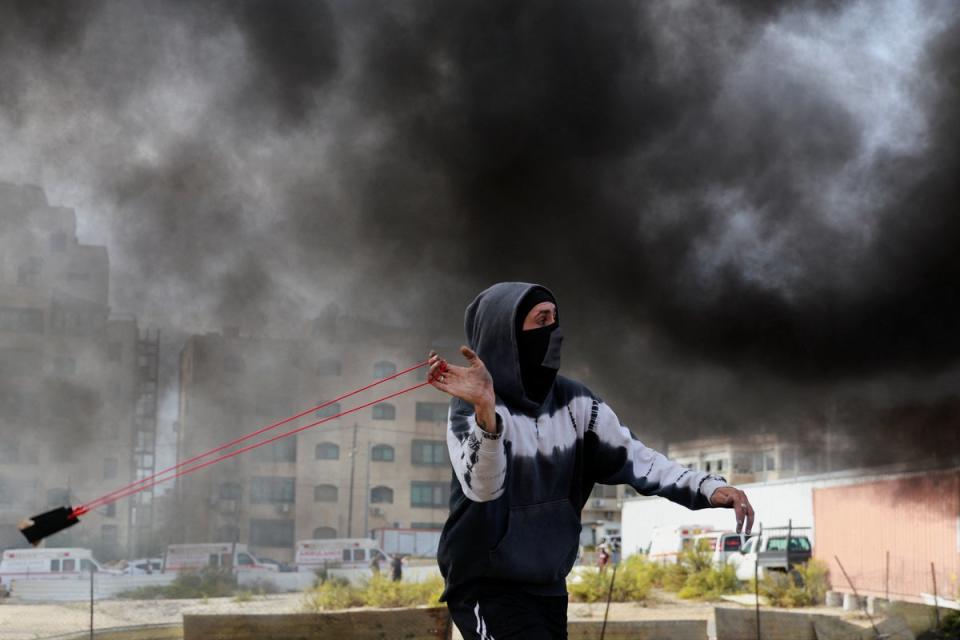 A Palestinian uses a sling to hurl stones during clashes with Israeli forces near Ramallah (Reuters)