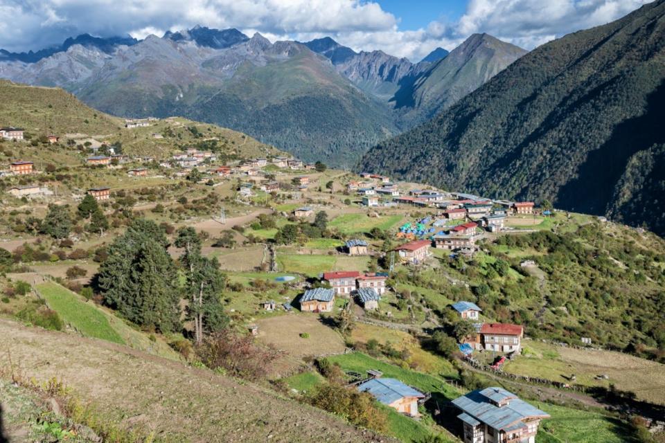 An aerial view of the village of Laya in Bhutan surrounded by greenery and mountains.
