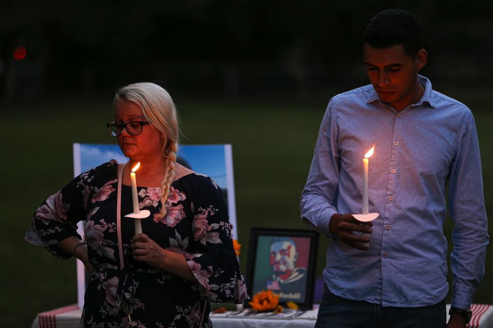 Adil Dghoughi's girlfriend, Sarah Todd, left, and brother Othmane Dghoughi, right, hold candles at a vigil for Adil Dghoughi in Martindale on Oct. 24, 2021.