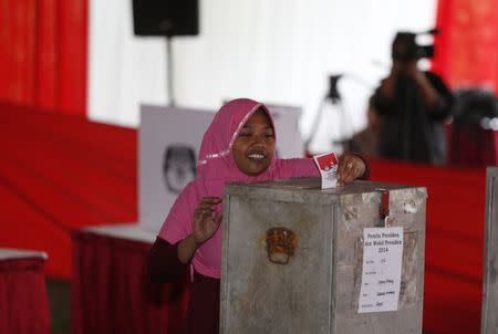 A woman puts her ballot into a voting box during the country's presidential election at Bojong Koneng polling station in Bogor July 9, 2014. REUTERS/Beawiharta