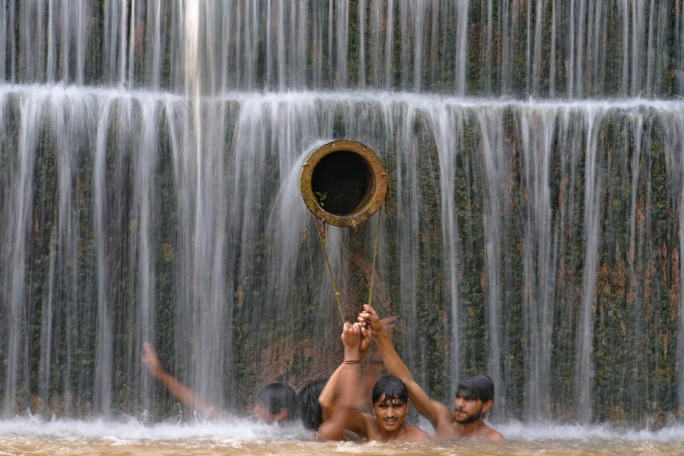 Young men cool themselves off in a waterfall as temperatures reached 36 C. (96.8 F.) in Islamabad, Pakistan, Friday, July 14, 2023. (AP Photo/Anjum Naveed)