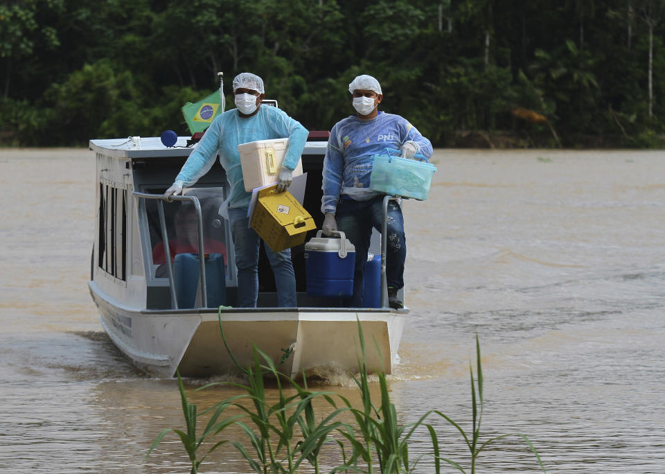 Healthcare workers Diego Feitosa Ferreira, 28, right, and Clemilton Lopes de Oliveira, 41, arrive on a boat to the Santa Rosa community, Amazonas state, Brazil, Friday, Feb. 12, 2021, to vaccinate residents with the Oxford-AstraZeneca COVID-19 vaccine. Navigating complex waterways to reach remote communities in Brazil’s Amazon is only the first challenge for the healthcare workers vaccinating Indigenous and riverine people against the new coronavirus. (AP Photo/Edmar Barros)