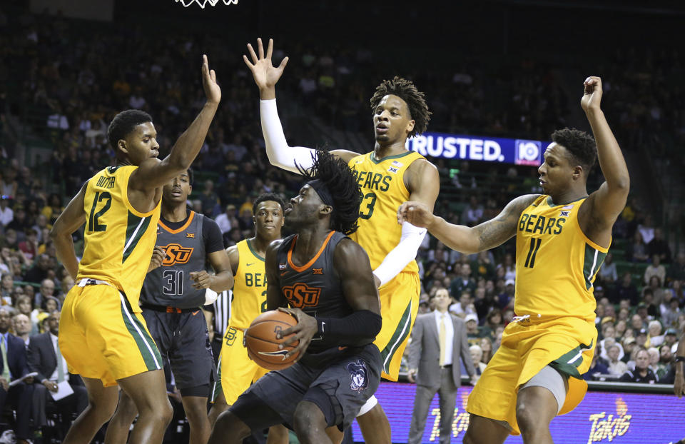 Oklahoma State guard Isaac Likekele, center, is guarded by Baylor's Jared Butler, left, Freddie Gillespie and Mark Vital, right, during the first half of an NCAA college basketball game Saturday, Feb. 8, 2020, in Waco, Texas. (AP Photo/Rod Aydelotte)