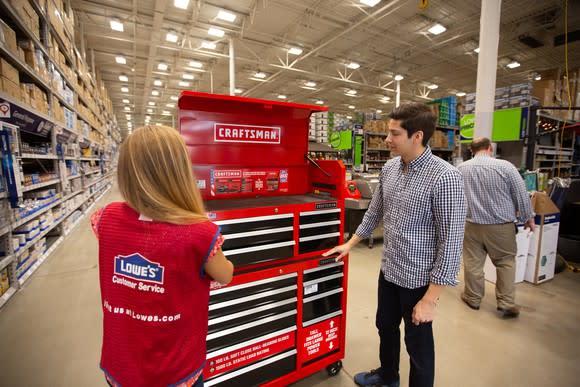 A Lowe's employee and a customer looking at a Craftsman tool storage unit in a Lowe's store.