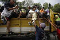 Migrantes hondureños con destino a la frontera de Estados Unidos suben a la parte trasera de un camión en Zacapa, Guatemala, el miércoles 17 de octubre de 2018. (AP Foto / Moises Castillo)