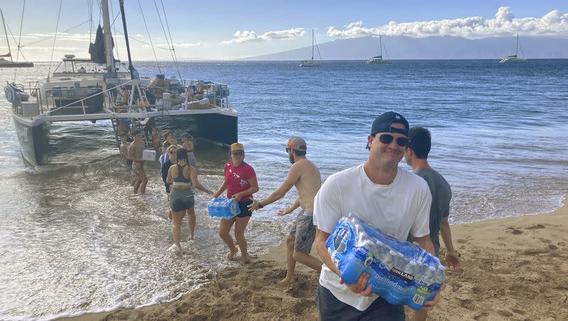 A group of volunteers who sailed from Maalaea Bay, Maui, form an assembly line on Kaanapali Beach on Saturday Aug. 12, 2023, to unload donations from a boat. Maui residents have come together to donate water, food and other essential supplies to people on the western side of the island after a deadly fire destroyed hundreds of homes and left scores of people homeless.