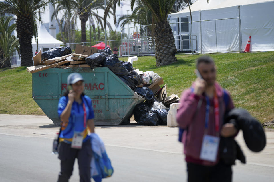 Personal acreditado camino al costado de un contenedor llenos de basura en el complejo del Estadio Nacional durante los Juegos Panamericanos en Santiago, Chile, el sábado 21 de octubre de 2023. (AP Foto/Silvia Izquierdo)