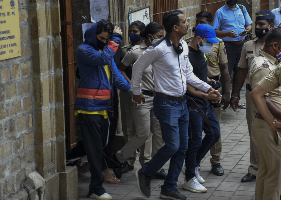 Bollywood actor Shah Rukh Khan’s son Aryan Khan, left, is escorted by law enforcement officials outside the Narcotics Control Bureau (NCB) to appear before a court in Mumbai, India, Monday, Oct.4, 2021. (AP Photo)