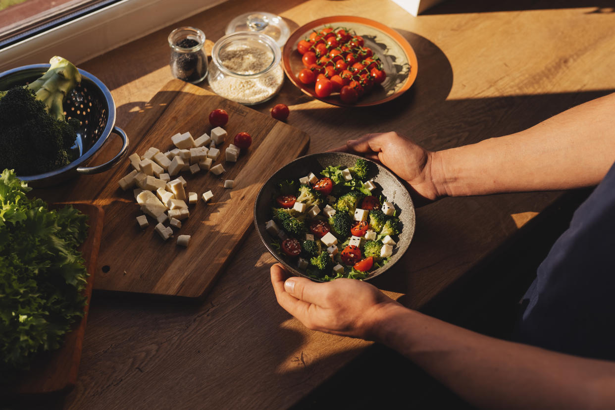 Man's hand scooping green salad. Healthy lifestyle and vegetarian vegan concept, Intermittent Fasting.�