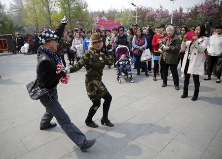 Seventy-nine-year-old Wang Baorong, dressed in military style clothes, dances with a man as she performs square dancing at a park square in Beijing, China, April 9, 2015. REUTERS/Kim Kyung-Hoon