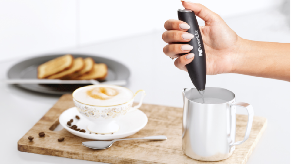 someone using the milk frother to create foam next to a frothy drink