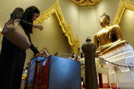 A woman donates her money into donation boxes at a temple in Bangkok, Thailand, Octoboer 18, 2017. Picture taken October 18, 2017. REUTERS/Athit Perawongmetha