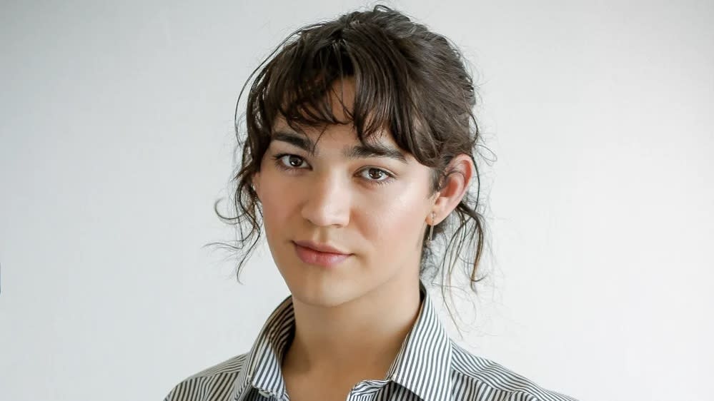 Miss Benny, wearing a blue and white striped shirt. Her hair is up and brown hair in a fringe.