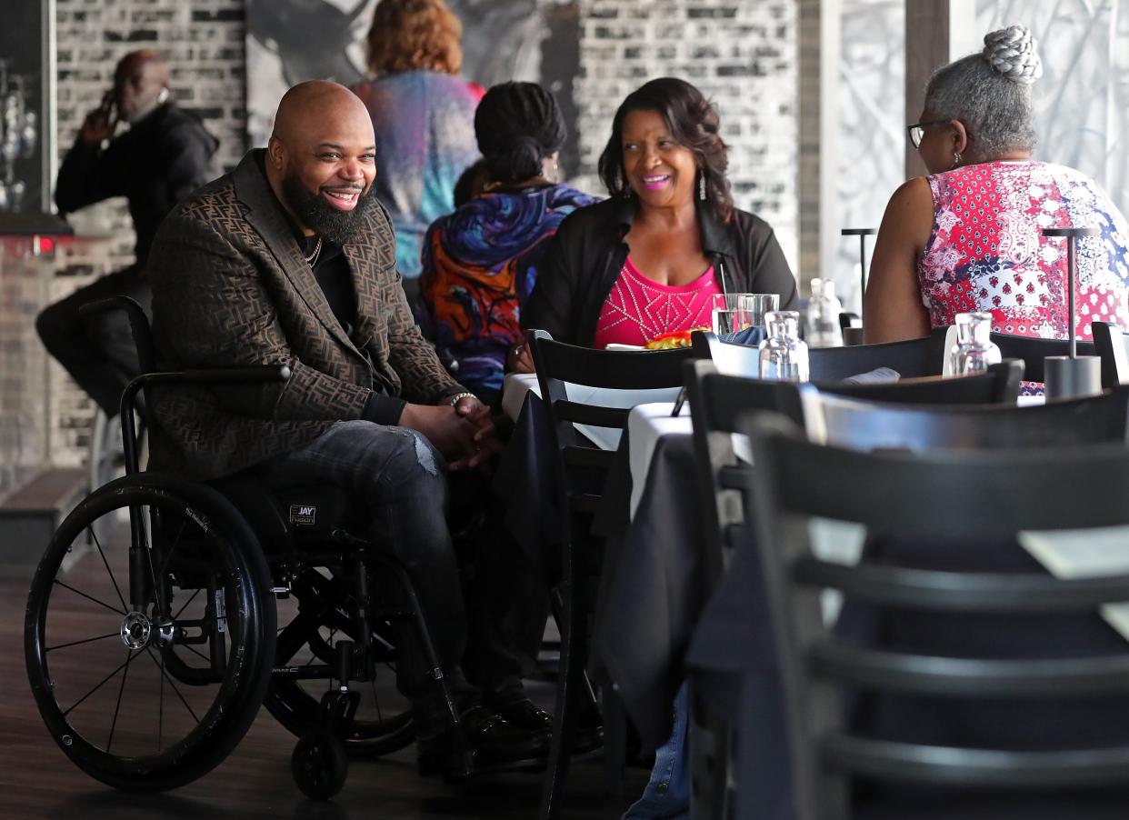 De'Juan Kelker II, left, makes his rounds greeting guests during his restaurant DeJuan's soft opening at Main and Exchange streets Thursday in Akron