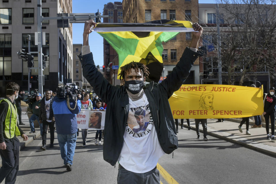 FILE — Tehilah Spencer, the brother of the late Peter Spencer, carries a Jamaican flag as he leads a rally calling for justice in his brother's death, in downtown Pittsburgh, Feb. 21, 2022. Venango County District Attorney D. Shawn White said Tuesday, that Peter Spencer was fatally shot while he was high on psychedelic mushrooms, and firing an assault rifle while threatening others at a cabin in Venango County in December 2021. No charges will be filed. (Pittsburgh Post-Gazette via AP, File)