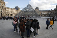 Visitors wait as striking employees demonstrate outside the Louvre museum Friday, Jan. 17, 2020 in Paris. Paris' Louvre museum was closed Friday as dozens of protesters blocked the entrance to denounce the French government's plans to overhaul the pension system. (AP Photo/Francois Mori)