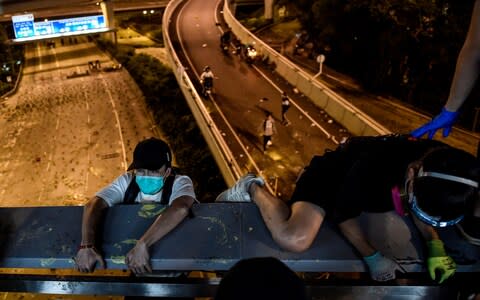 Protesters take a rope down from a bridge to a highway, to escape from Hong Kong Polytechnic University campus and the police - Credit: YE AUNG THU/AFP via Getty Images