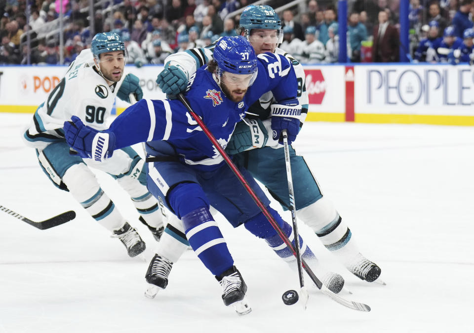 Toronto Maple Leafs defenseman Timothy Liljegren (37) is checked by San Jose Sharks forward Alexander Barabanov (94) during the first period of an NHL hockey game, Tuesday, Jan. 9, 2024 in Toronto. (Nathan Denette/The Canadian Press via AP)