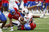 Texas Tech running back Tahj Brooks (28) is stopped by Kansas safety's O.J. Burroughs (5) and Marvin Grant (4) during the second half of an NCAA college football game, Saturday, Nov. 11, 2023, in Lawrence, Kan. (AP Photo/Colin E Braley)