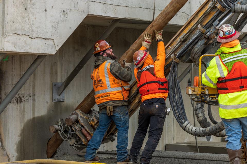 Workers help guide a hydraulic anchor drilling rig as part of the seismic mitigation effort at Puget Sound Naval Shipyard on Feb. 16, 2023.