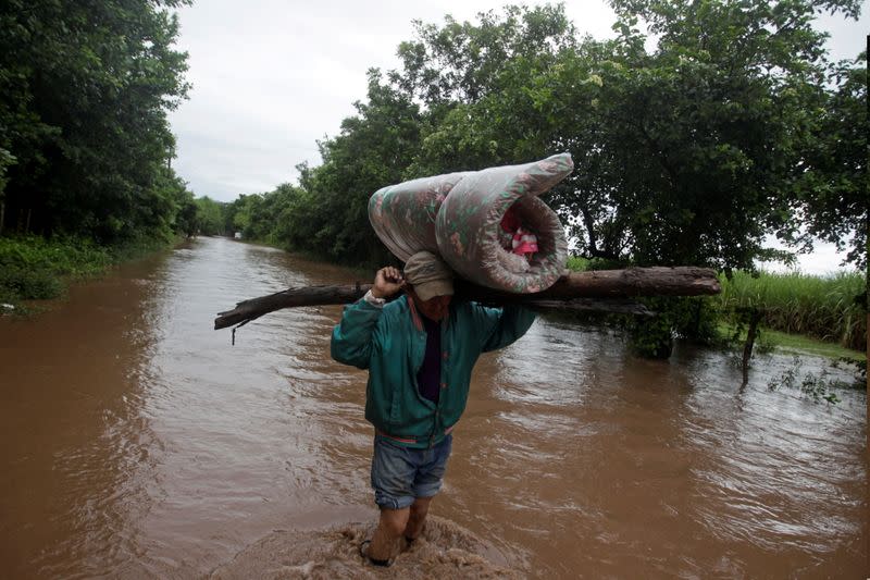 Un hombre lleva sus pertenencias por un camino inundado luego del paso de la Tormenta Iota, en Marcovia, Honduras