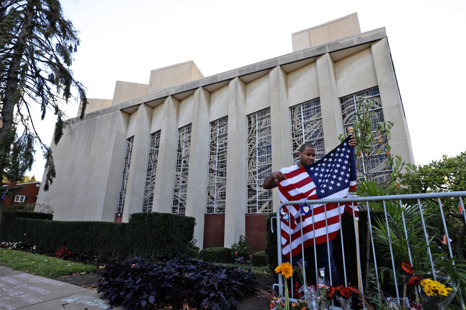 A man places an American flag outside the Tree of Life synagogue in Pittsburgh on Sunday, Oct. 27, 2019, the first anniversary of the shooting at the synagogue that killed 11 worshippers. (AP Photo/Gene J. Puskar)