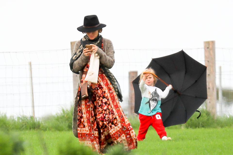 One of the twin boys seemed to be having fun playing with an umbrella, while mum Elsa was busy on her phone.