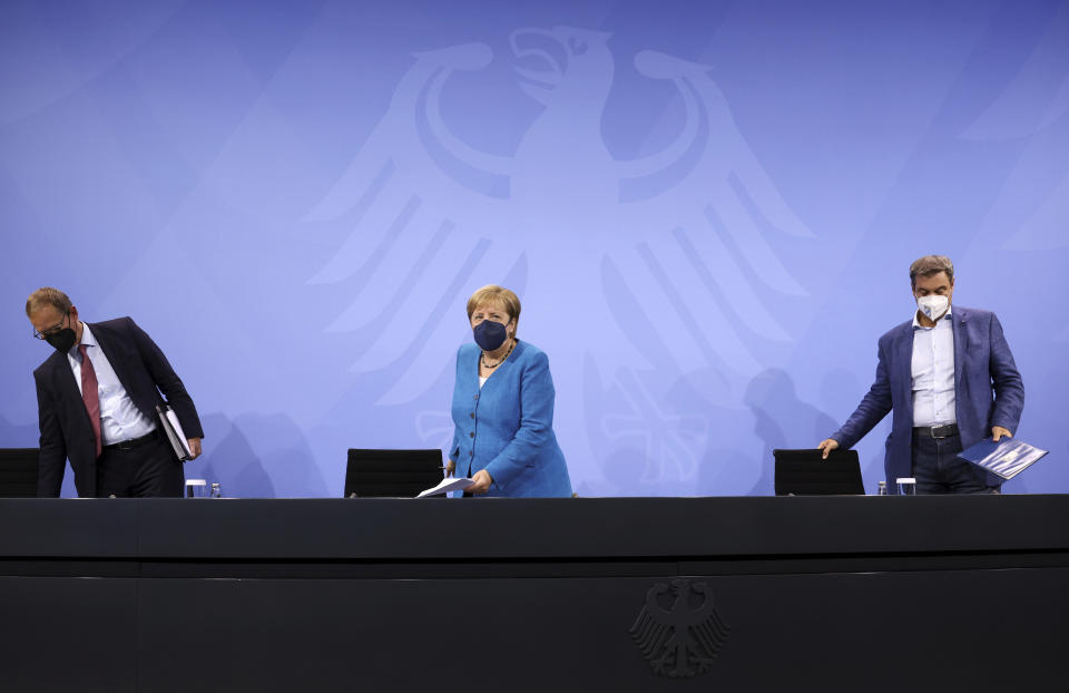 German Chancellor Angela Merkel, centre, arrives for a media conference with Bavarian State Premier Markus Soeder, right, and Berlin Mayor Michael Mueller, following talks with state leaders to discuss anti-coronavirus measures at the Chancellery in Berlin, Germany, Tuesday Aug. 10, 2021.(Christian Mang/Pool via AP)