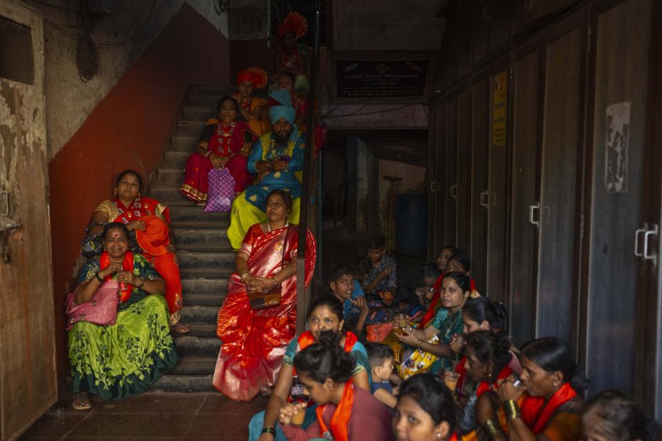 Supporters of the National Democratic Alliance sit on the staircase to shield themselves from the heat as their candidates arrive to file nomination papers ahead of national elections in Mumbai, India, Monday, April 29, 2024. (AP Photo/Rafiq Maqbool)
