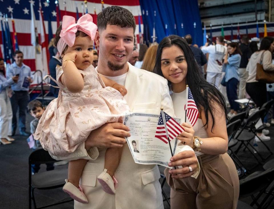 Andy Escalona Abreu, recién juramentado como ciudadano estadounidense, originario de Cuba, posa para fotos con su hija Leah Escalona de 10 meses y su esposa Talia López después de la ceremonia de naturalización a bordo del USS Battan en Miami.
