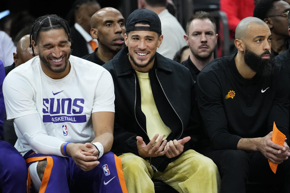 Phoenix Suns guard Devin Booker smiles from the bench during the second half of an NBA basketball game against the Charlotte Hornets, Tuesday, Jan. 24, 2023, in Phoenix. (AP Photo/Matt York)