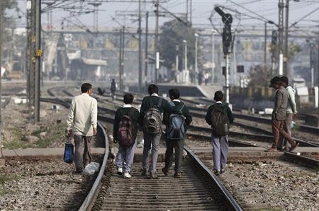 School children walk on tracks at a railway station in New Delhi February 18, 2014. REUTERS/Adnan Abidi