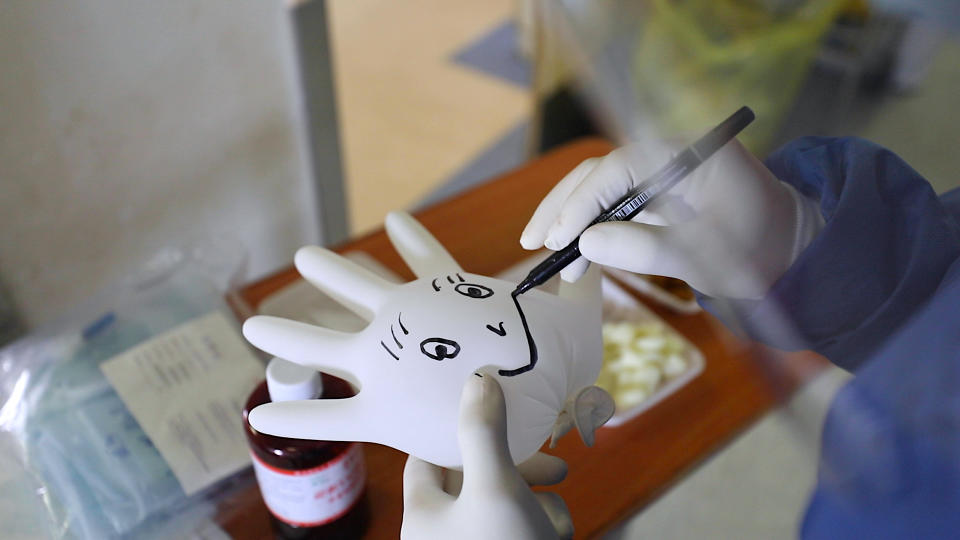 Nurse drawing a smiley face on a medical glove to raise spirits of hospitalized coronavirus patients in a hospital in Wuhan, China. As seen in 76 Days, directed by Hao Wu, Weixi Chen and Anonymous. Image courtesy of 76 Days LLC.