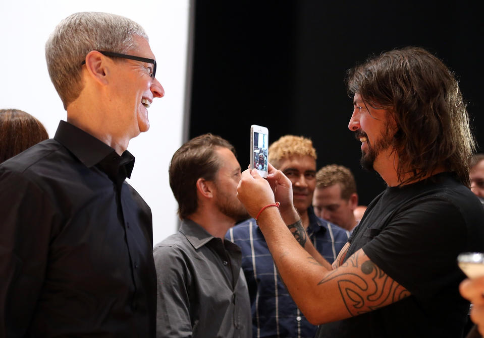 SAN FRANCISCO, CA - SEPTEMBER 12: Apple CEO Tim Cook (L) looks on as Dave Grohl of the Foo Fighters looks at the new iPhone 5 during an Apple special event at the Yerba Buena Center for the Arts on September 12, 2012 in San Francisco, California. Apple announced the iPhone 5, the latest version of the popular smart phone. (Photo by Justin Sullivan/Getty Images)