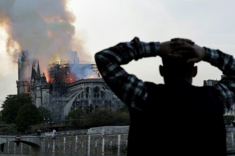 Un passant regarde Notre-Dame en flammes le 15 avril 2019 - Geoffroy VAN DER HASSELT © 2019 AFP