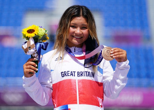 Sky Brown, holding a bunch of flowers and a bronze medal, stands on the podium