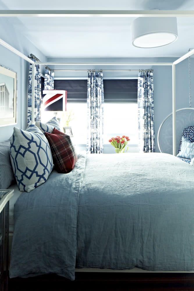 This publicity image released by Brian Patrick Flynn shows a bedroom designed with a blue-grey paint color called Drenched Rain from Dunn-Edwards. The bed, with washed linen, adds a lived in, casual look. Flynn often layers washed out blue tones with navy and white to create a summer-inspired aesthetic. (AP Photo/Brian Patrick Flynn, Daniel Collopy)
