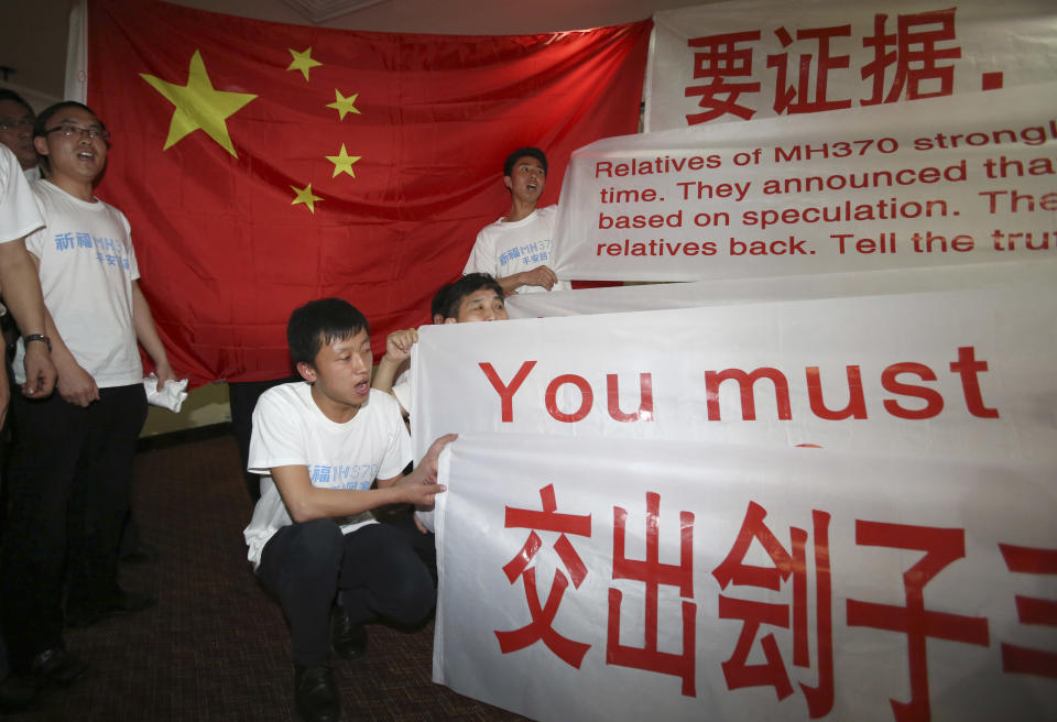 Newly arrived Chinese relatives of passengers on board the missing Malaysia Airlines flight MH370 shouts slogans as they speak to reporters at a hotel in Subang Jaya, Malaysia, Sunday March 30, 2014. Several dozen Chinese relatives of passengers on Flight 370 arrived in Malaysia Sunday to demand more information about what happened to the airliner that has been missing for more than three weeks, saying there has not been enough information on what happened to their loved ones. Shirts worn by the relatives read: "Praying that MH370 returns home safely." (AP Photo/Aaron Favila)