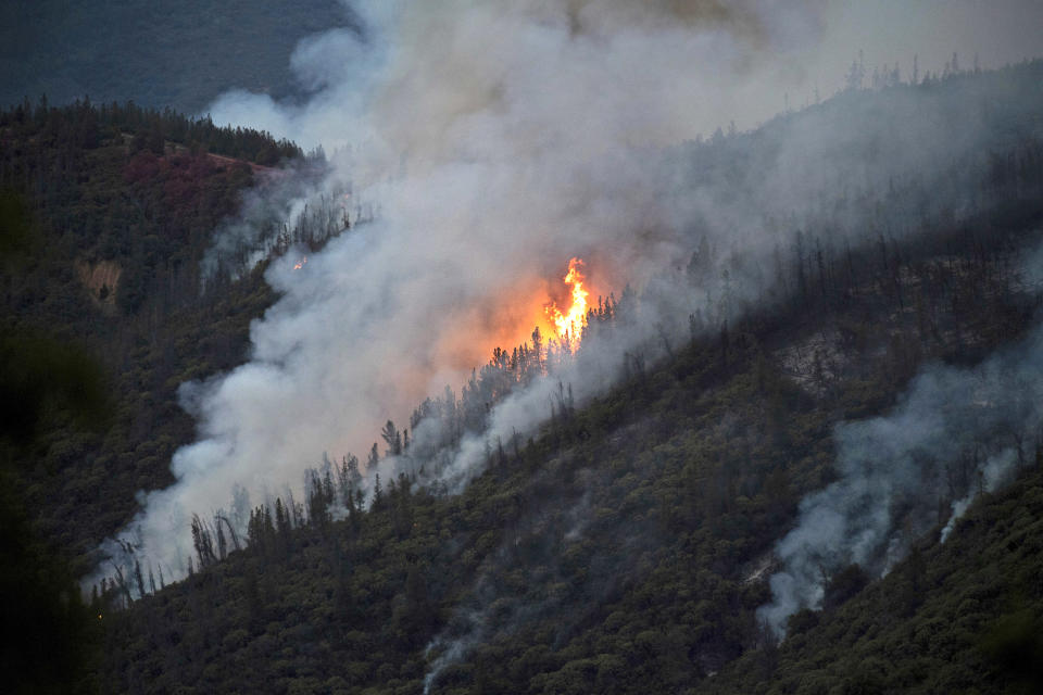 FILE - In this Sunday, July 15, 2018, file photo, flames from a wildfire burn down a hillside in unincorporated Mariposa County Calif., near Yosemite National Park. California authorities will shut down Yosemite Valley for several days beginning Wednesday, July 25, as crews try to stop a stubborn and growing wildfire from spreading into Yosemite National Park. (AP Photo/Noah Berger, File)