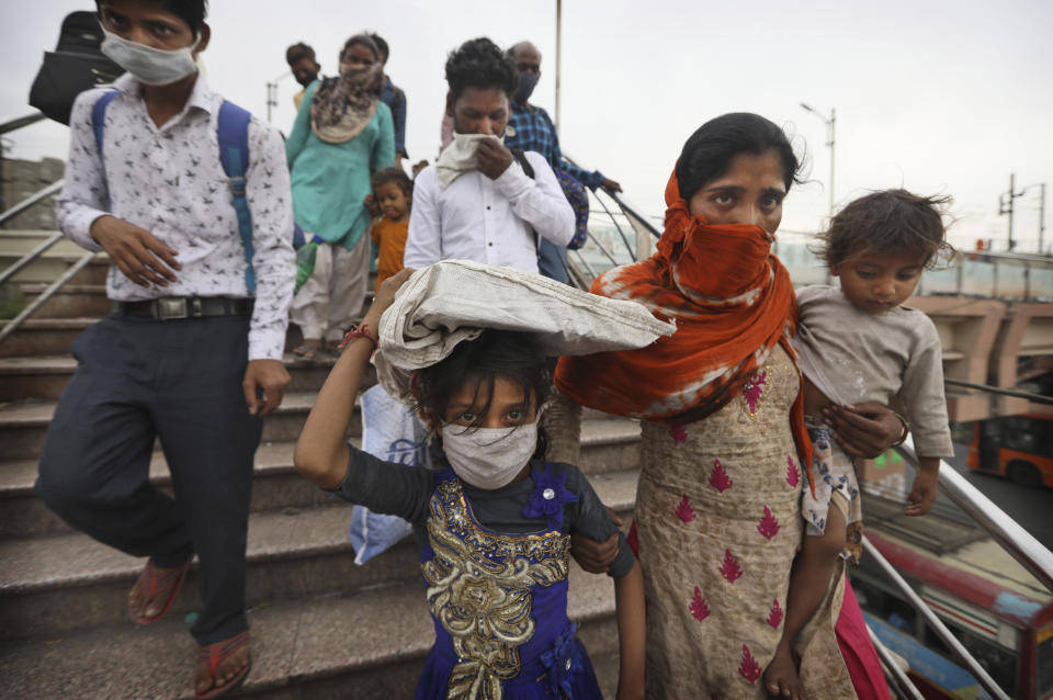 Migrant workers cross a pedestrian bridge leading to a bus station as they walk to board buses for their respective villages following a lockdown for six days in New Delhi, India, Tuesday, April 20, 2021. India has been overwhelmed by hundreds of thousands of new coronavirus cases daily, bringing pain, fear and agony to many lives as lockdowns have been placed in Delhi and other cities around the country. (AP Photo/Manish Swarup)