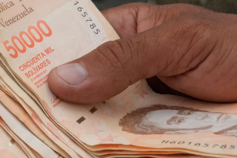 En esta imagen de archivo, tomada el 5 de agosto de 2021, un hombre cuenta billetes por el equivalente a un dólar en una parada de ómnibus en Caracas, Venezuela. (AP Foto/Ariana Cubillos, archivo)