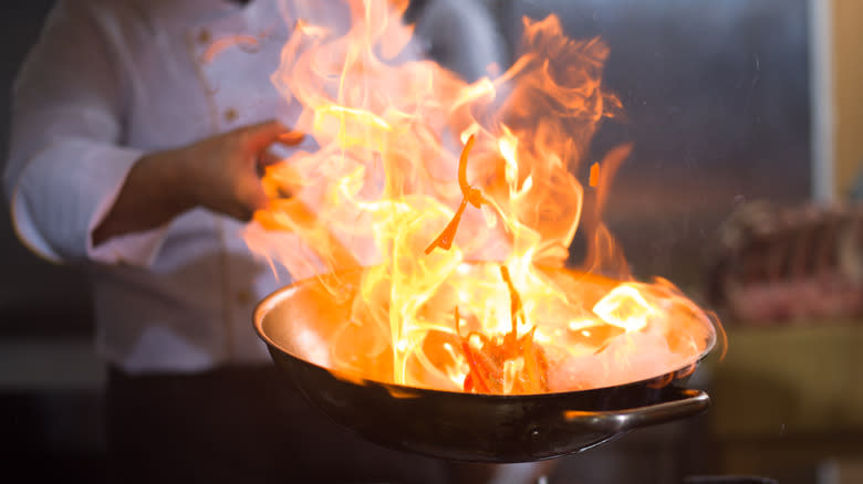 Chef holding flaming pan